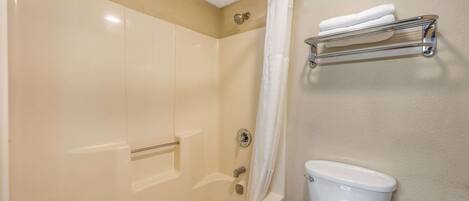 A bathroom with a bathtub, shower curtain, toilet, and a towel rack.