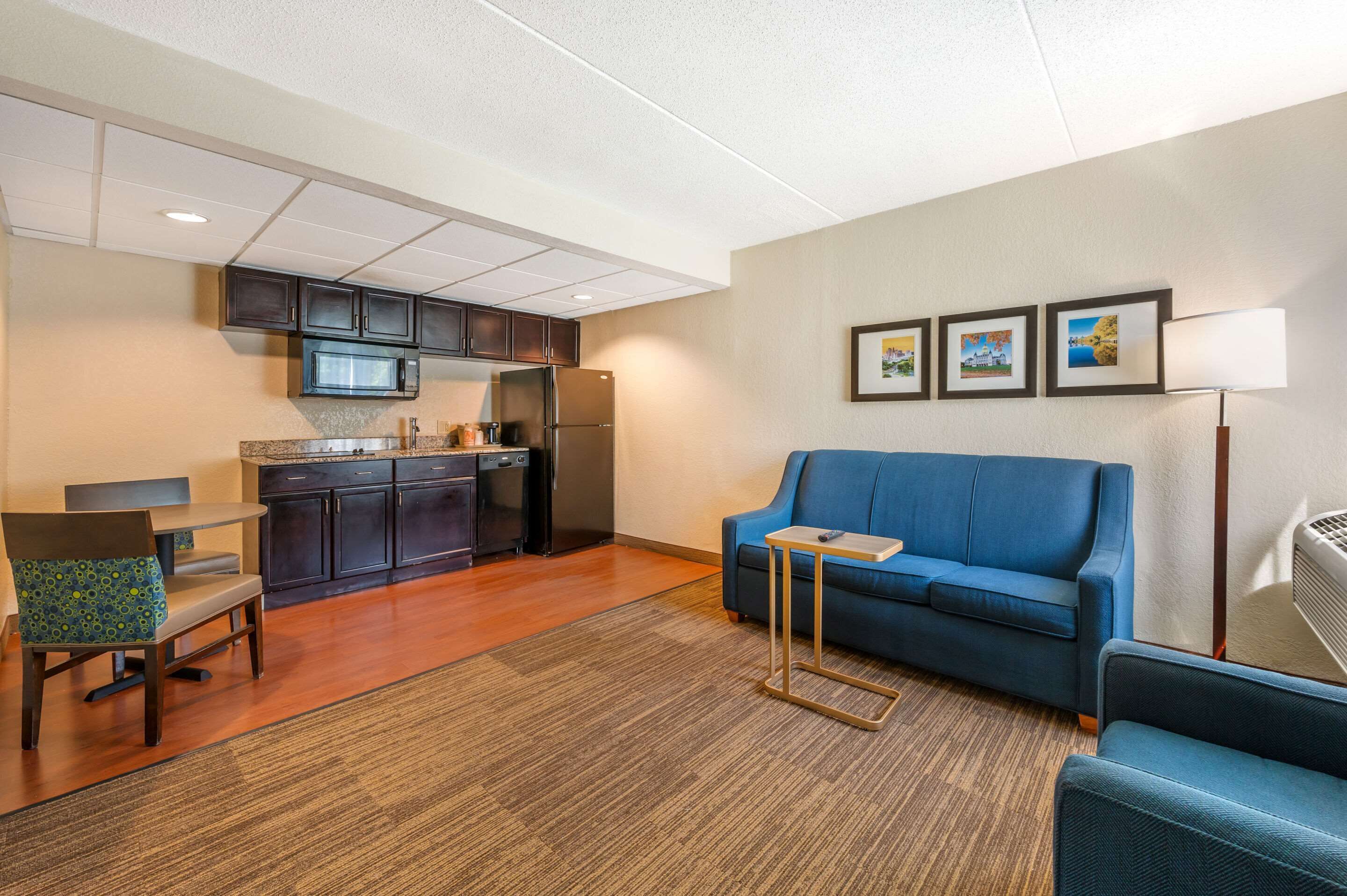 Un espacio habitable compacto con kitchenette, un sofá azul, una mesita y una silla.