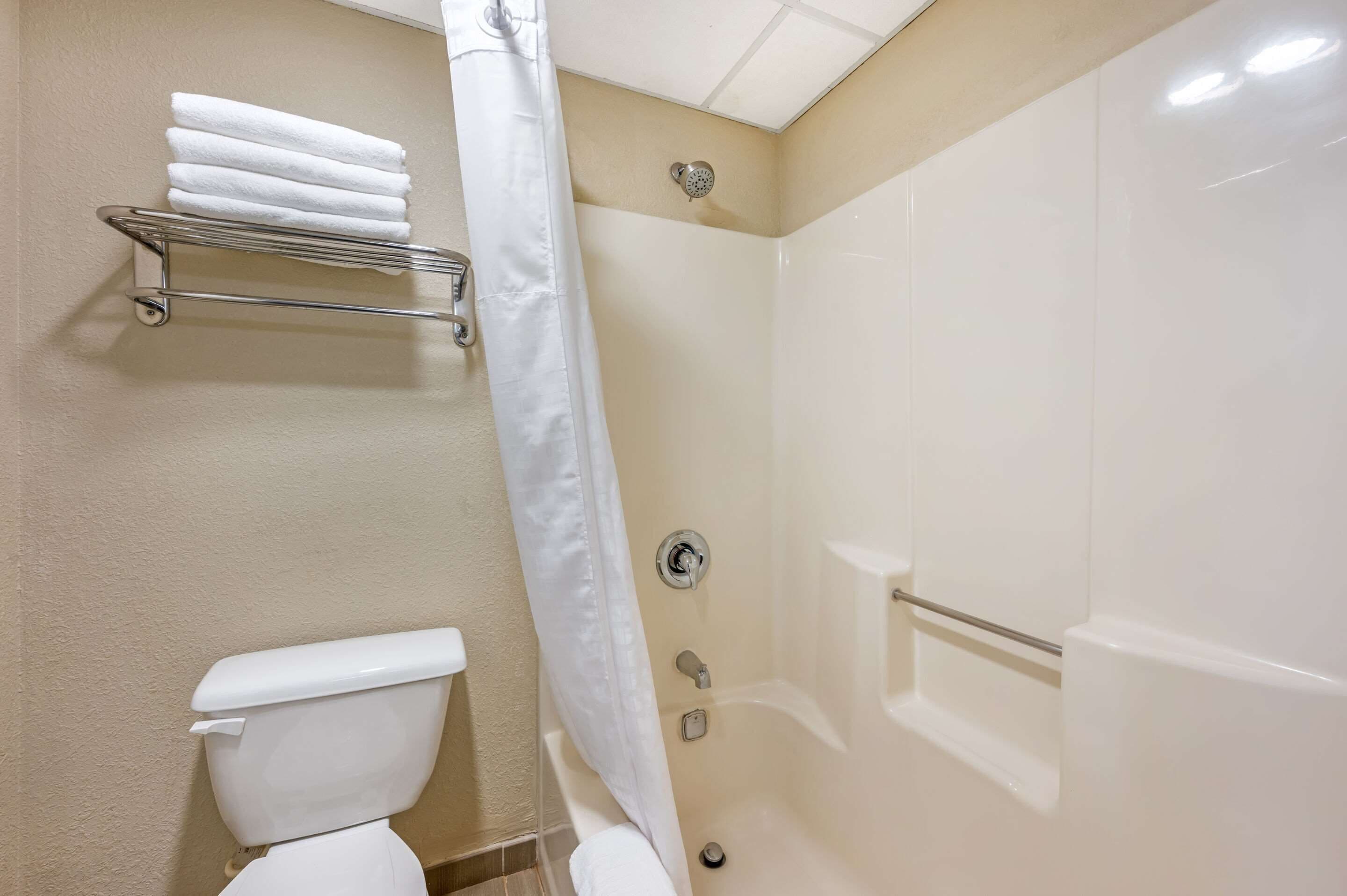 A bathroom with a toilet, a shower stall, and a towel rack with multiple towels.