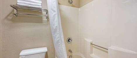A bathroom with a toilet, a shower stall, and a towel rack with multiple towels.