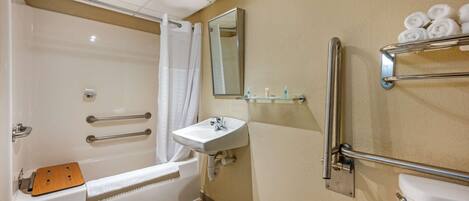 A bathroom with a bathtub, a sink, a mirror, and a towel rack.