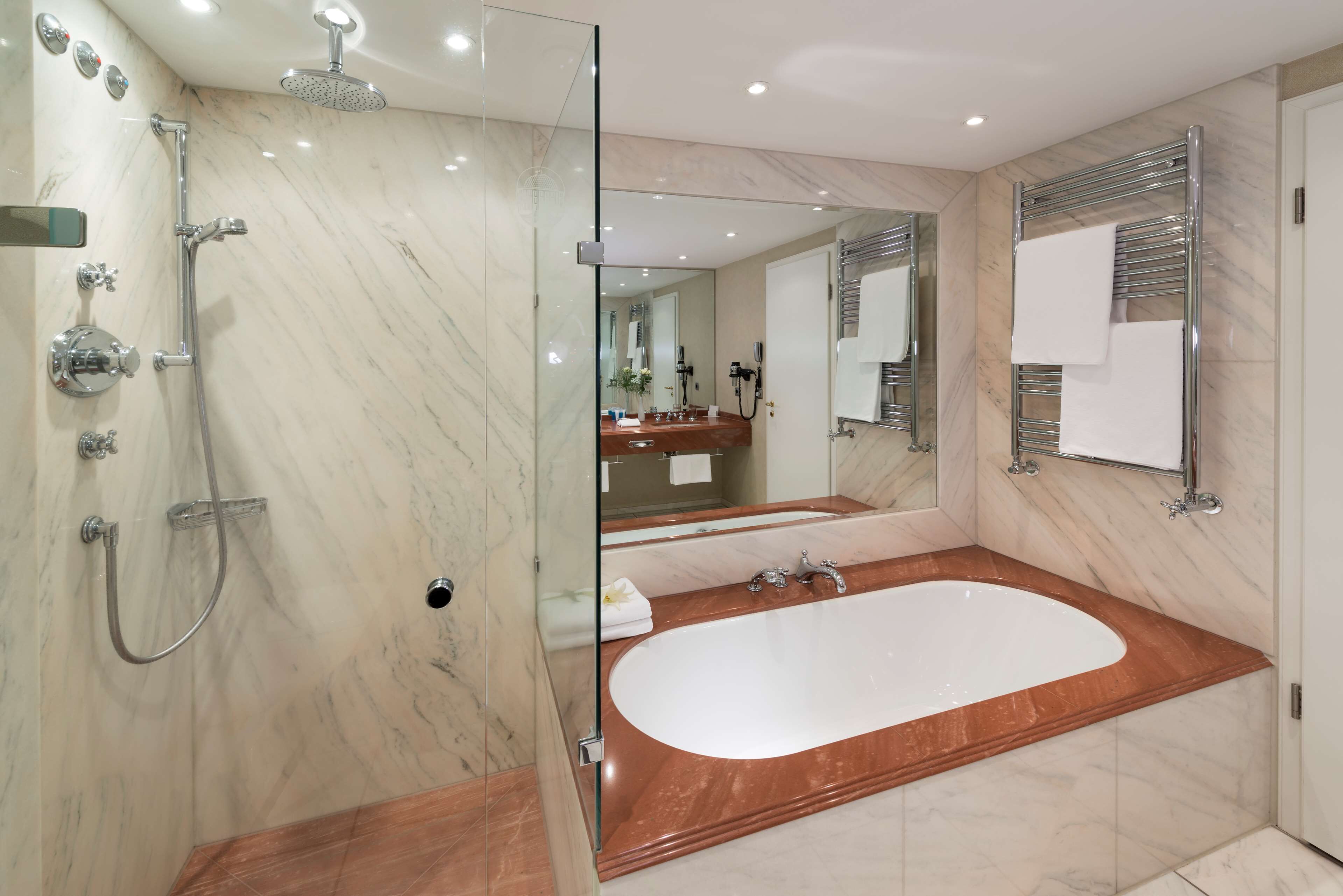 Een moderne badkamer met een douchecabine, een vrijstaand ligbad en een wastafel met spiegel.