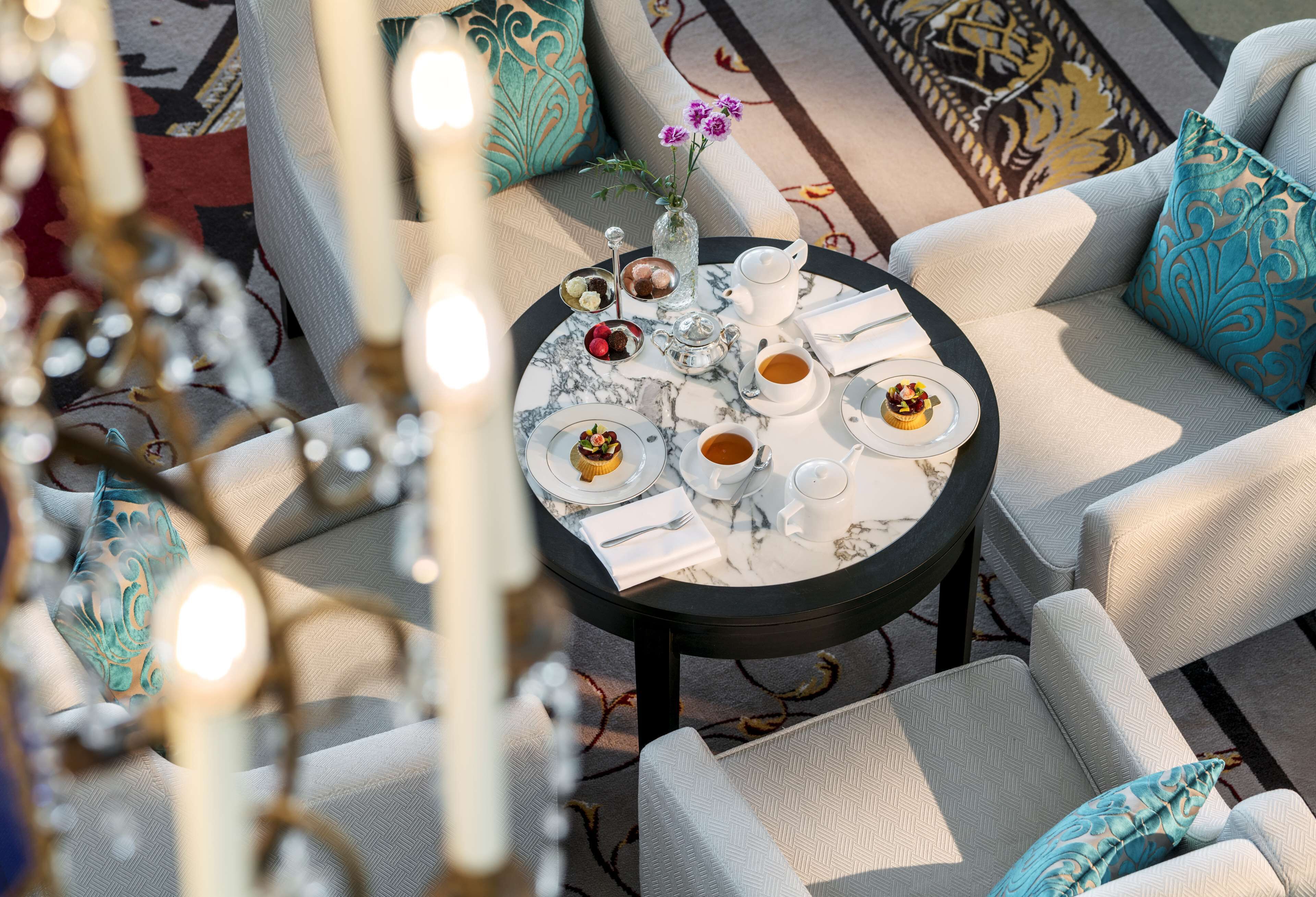 A round table with a marble top, surrounded by light-colored upholstered chairs.
