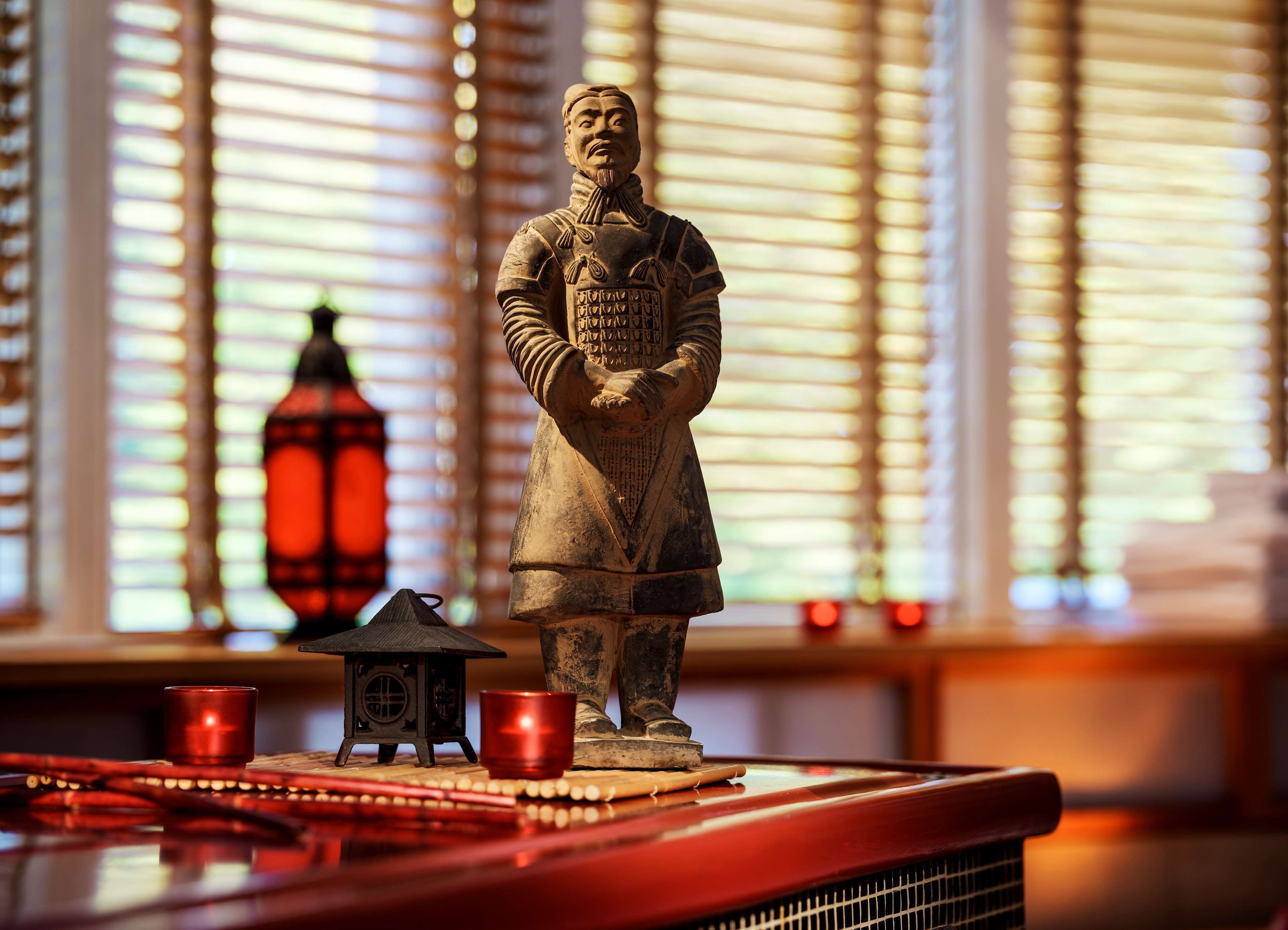 A statue of a historical figure on a table with a lantern and cups.