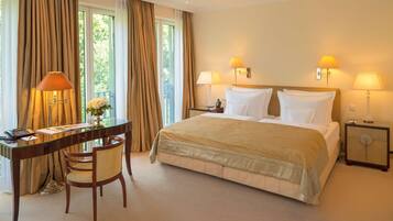 A hotel room with a bed, two bedside lamps, a desk with a telephone, and a chair.