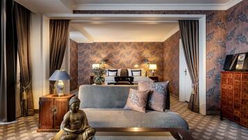 Quarto com sofá, estátua de Buda, armário de madeira e cama com papel de parede estampado.