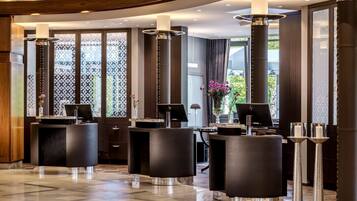 A modern lobby with a reception desk, black seating, and decorative vases.