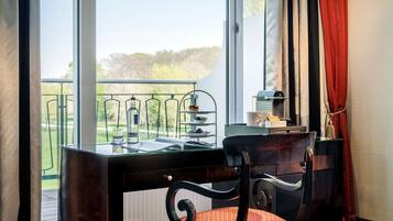 Ein Zimmer mit Schreibtisch, Stuhl und Blick auf einen Balkon mit Gartenmöbeln.