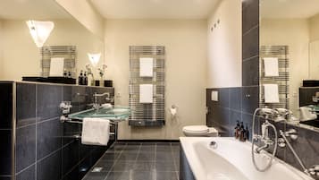 A modern bathroom with a glass shower, a large bathtub, and a toilet.