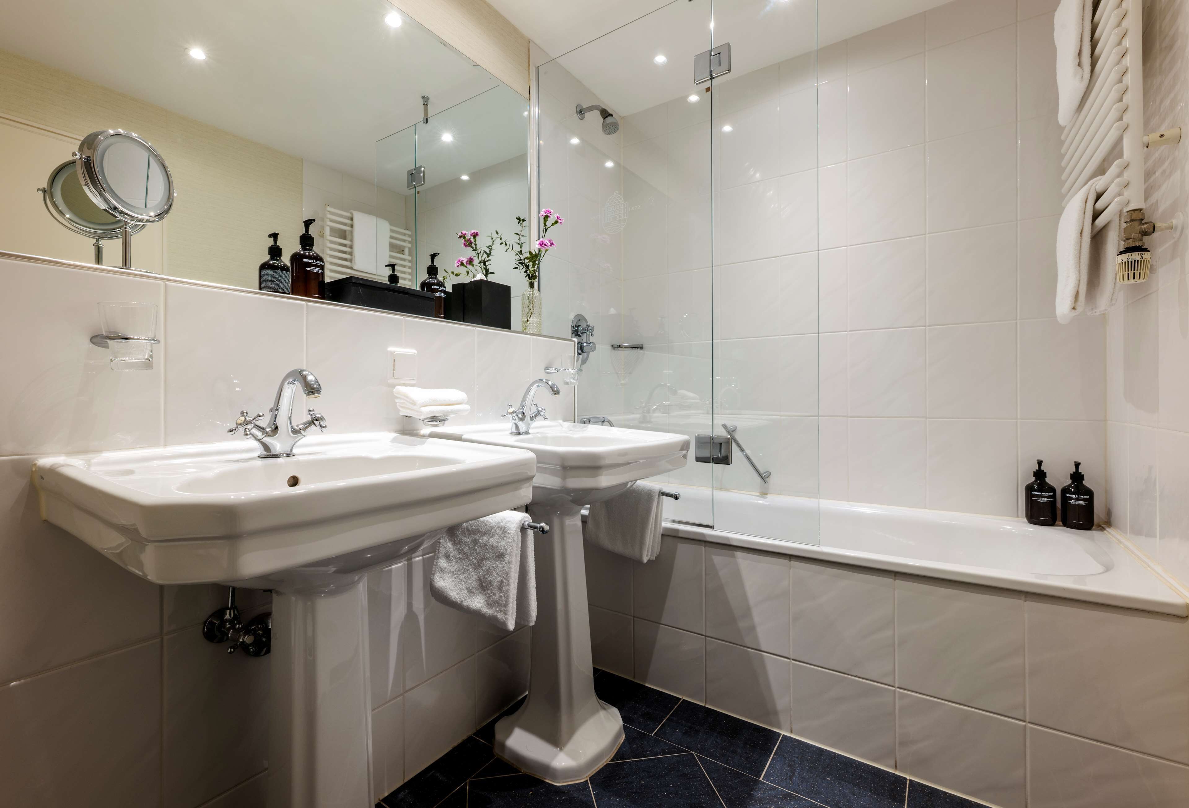 A modern bathroom with two sinks, a large mirror, a shower, and a bathtub.