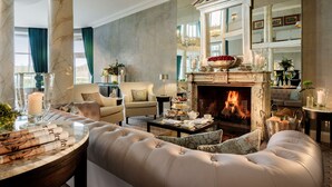 Un salón lujoso con chimenea, asientos cómodos y una moldura de chimenea de mármol.