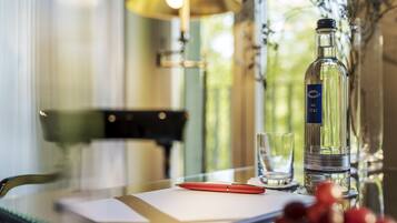 A table with a bottle, a glass, and a red pen.