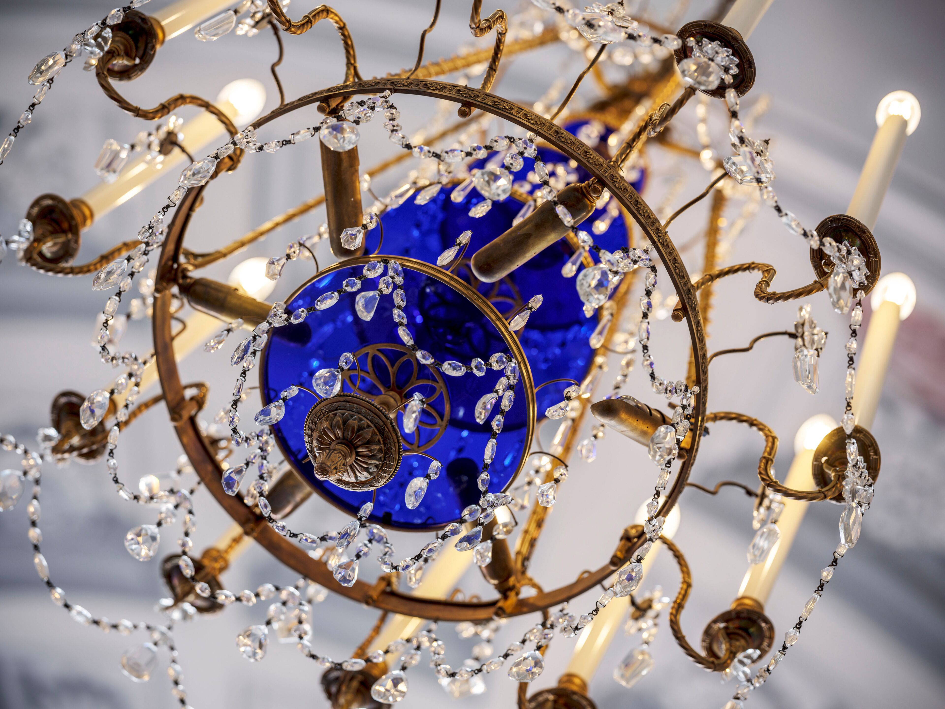 Un lustre orné de décorations en cristal et d’un élément décoratif en verre bleu.