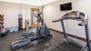 Ein Fitnessraum mit Laufband, Crosstrainer und verschiedenen Trainingsbällen.