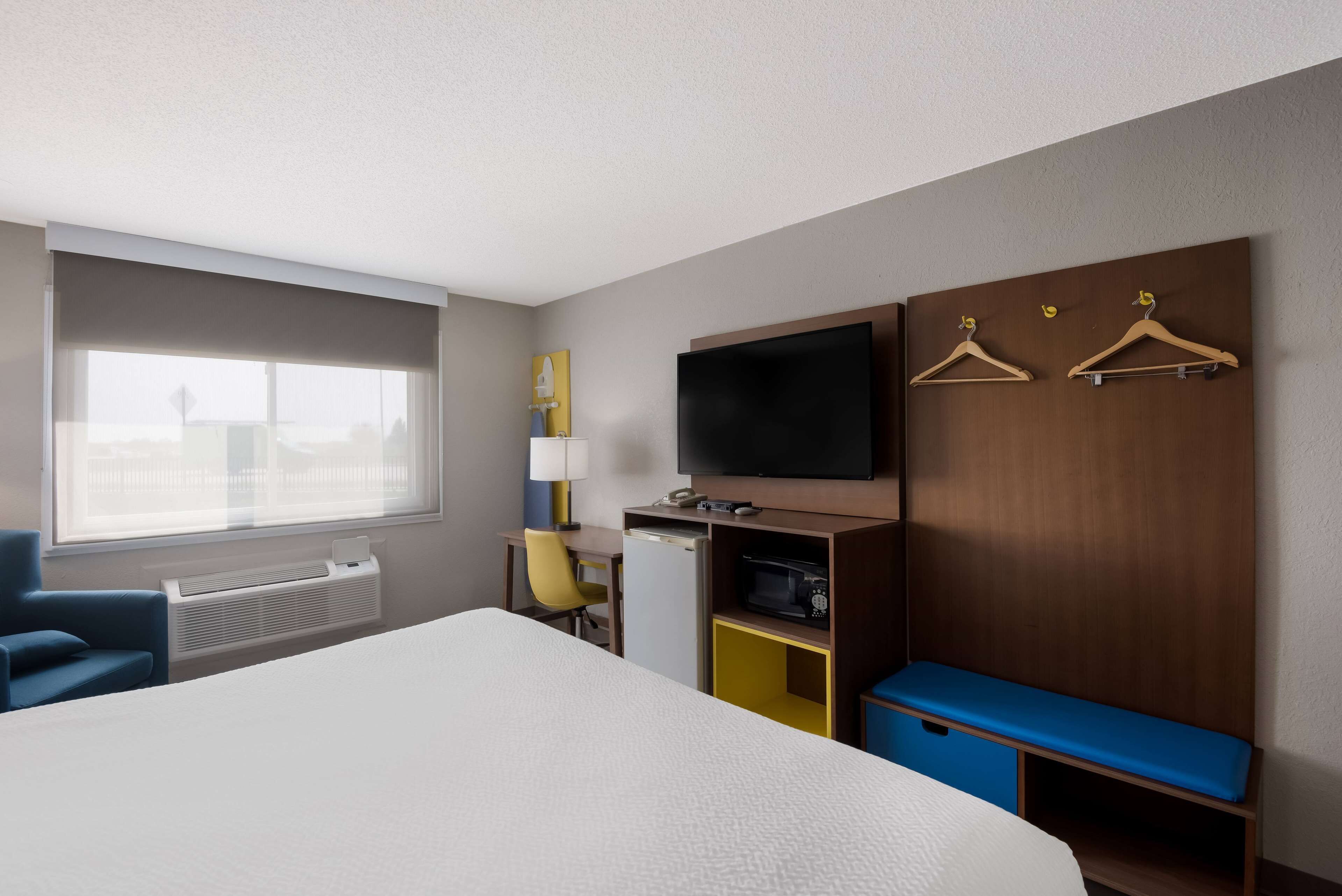 Una camera d'albergo con un letto grande, una TV fissata al muro, una scrivania con una sedia e una finestra vista sulla città.