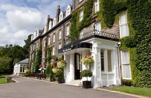 A traditional building with a white facade, ivy-covered walls, and a black awning. - Classic Lodges The Old Swan Hotel (Harrogate)