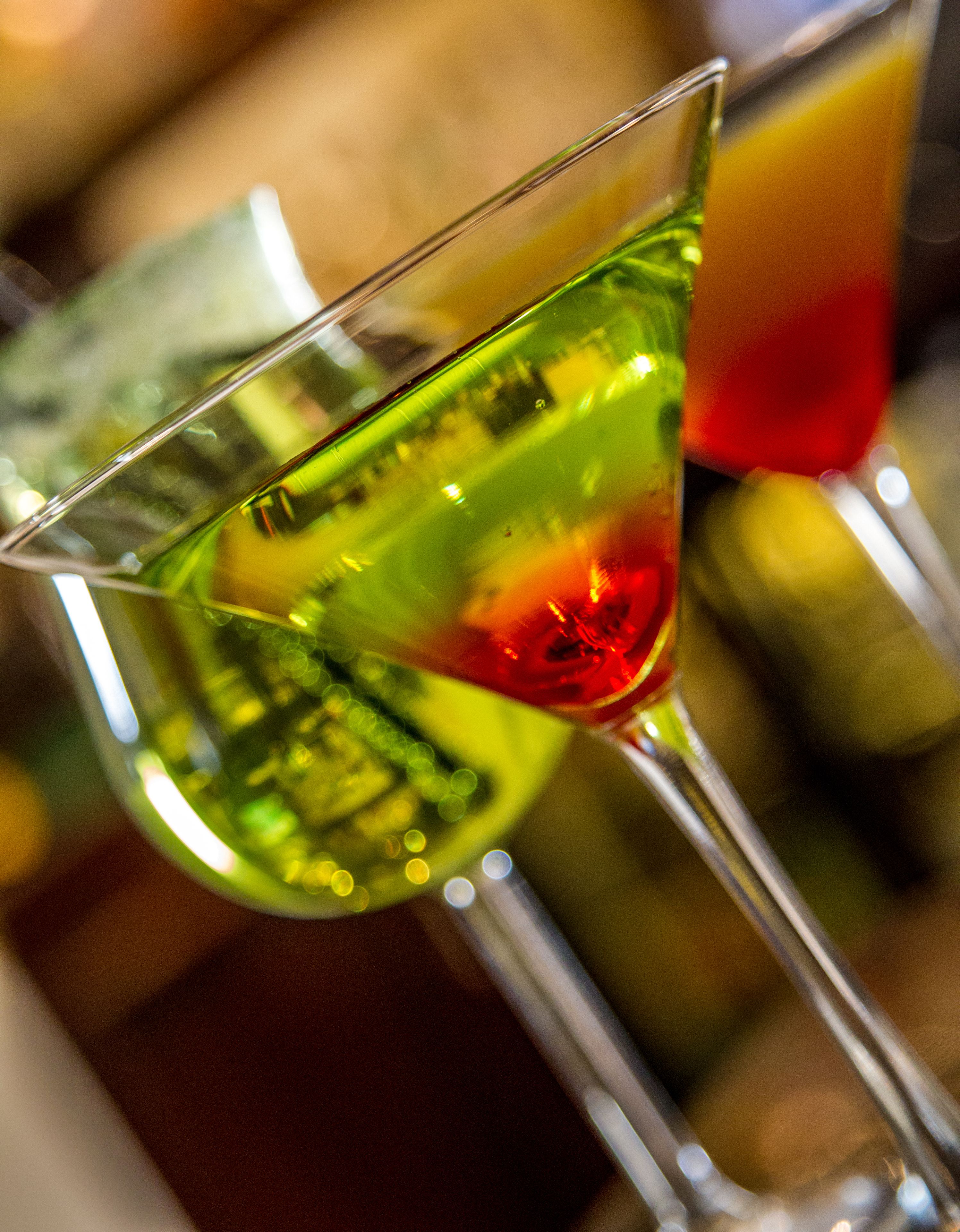 A martini glass with a green liquid and a red garnish.