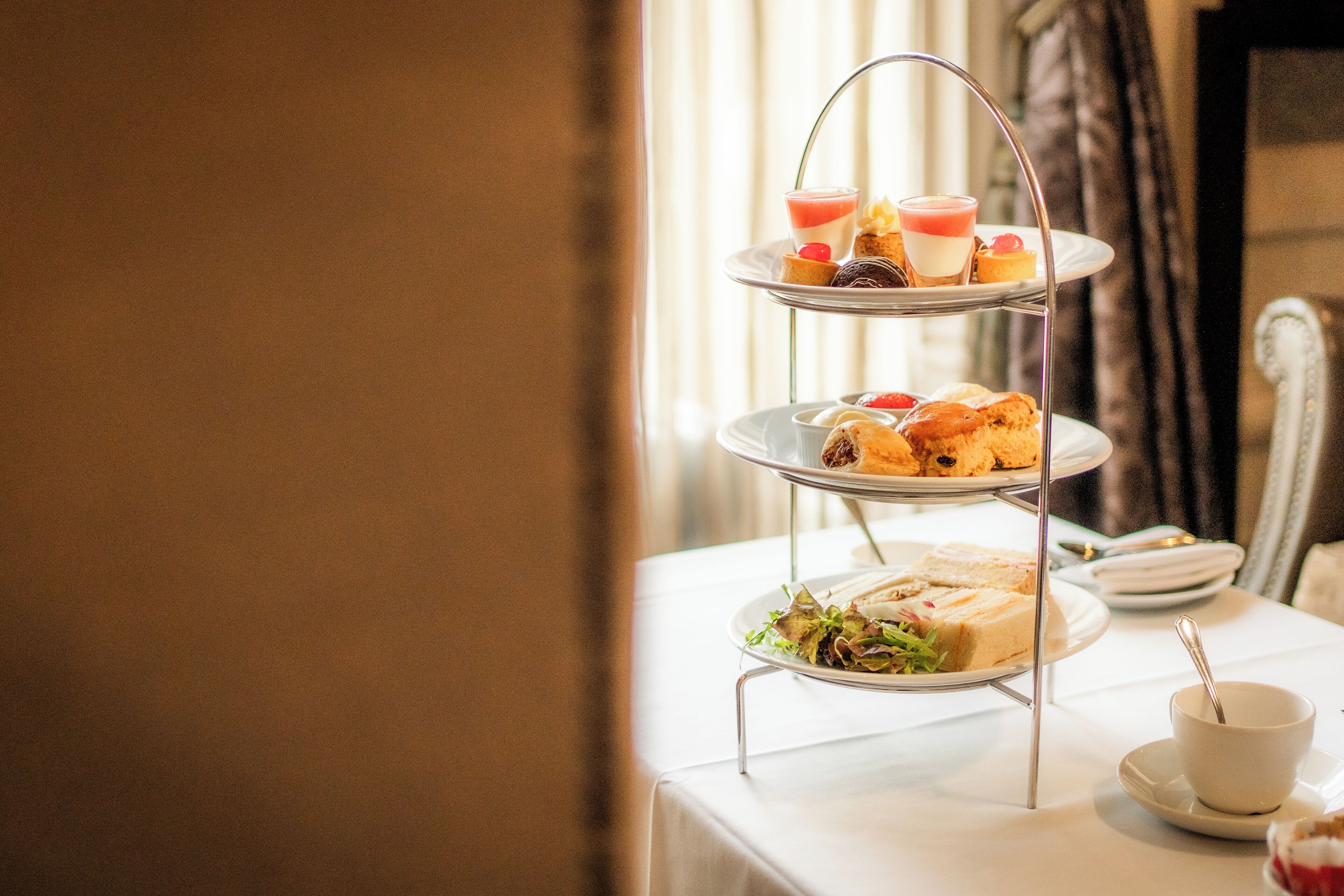 A three-tiered dessert stand with various pastries and desserts on a table.