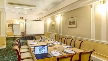 A conference room with a long table, chairs, a projector screen, and a laptop.