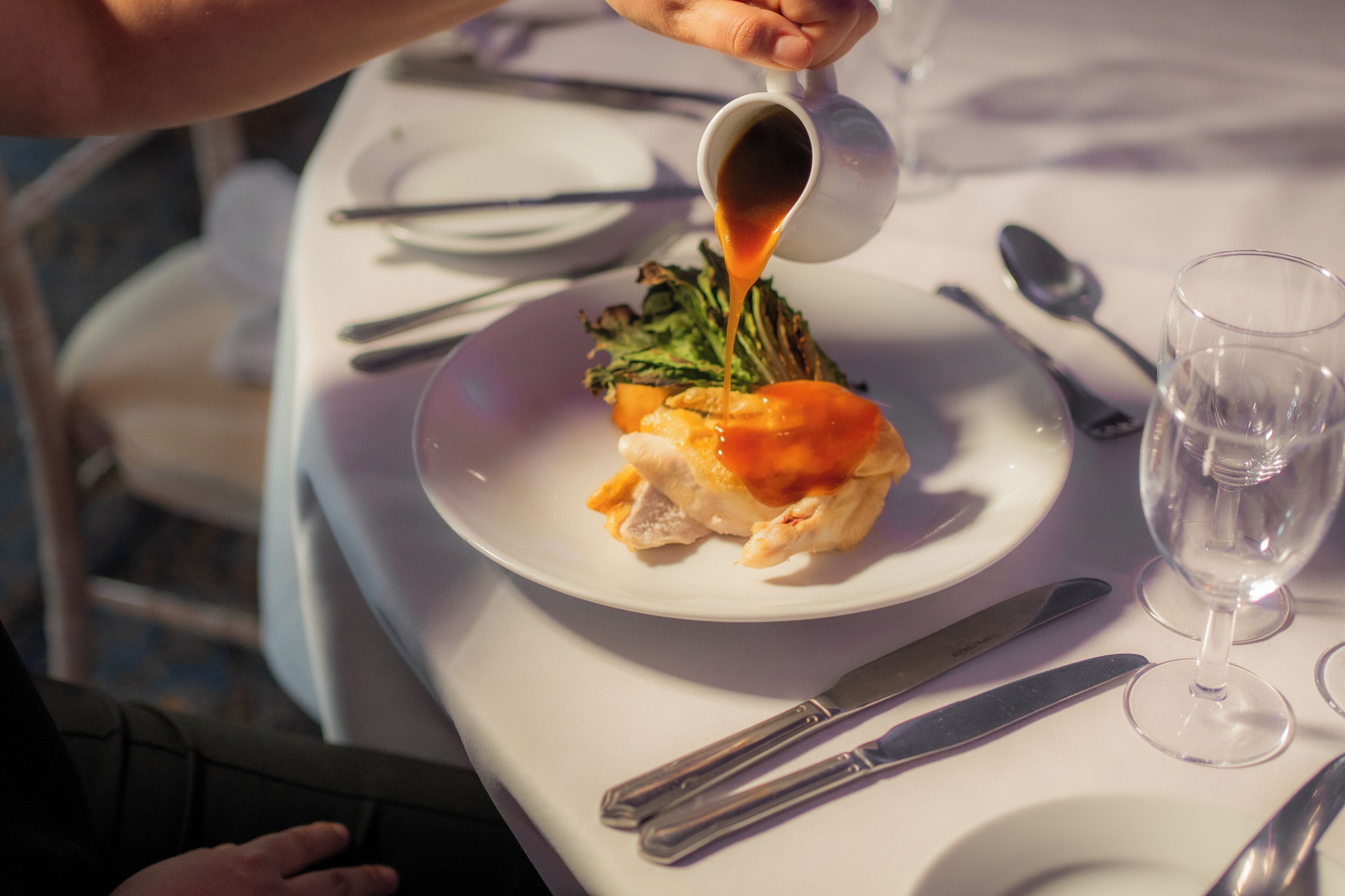 A dining table with a plate of food, a glass of water, and cutlery.