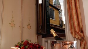 A dining table with a tray, a bowl of strawberries, a bottle of champagne, and a glass. - Hotel Ambassador Tre Rose (Venice)