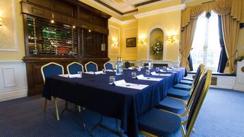 A conference room with a long table, blue chairs, and a chandelier.