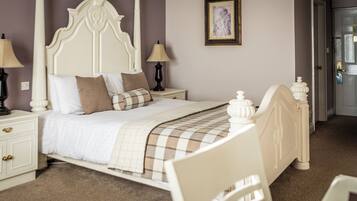 A bedroom with a bed, nightstands, a lamp, a picture on the wall, and a door.