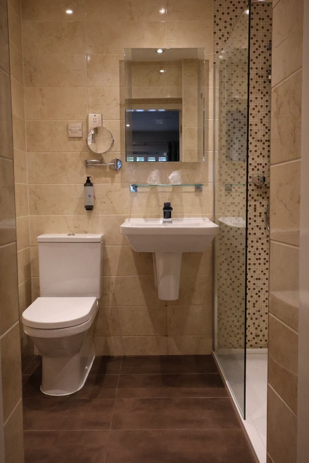 Un baño con inodoro, lavamanos y cabina de ducha de vidrio.