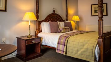 A neatly made bed with a plaid blanket, two bedside tables with lamps, and a wooden headboard.