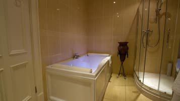 Un baño con bañera, cabina de ducha con mampara de vidrio y un inodoro.