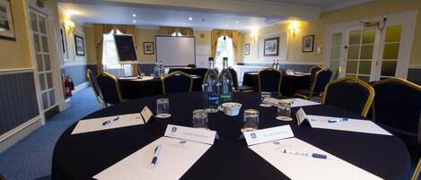 A conference room with a round table, name cards, and water bottles.
