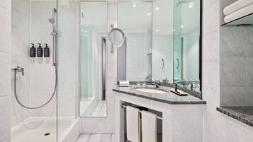 Un baño moderno con cabina de ducha acristalada, un espejo grande y encimera de granito.