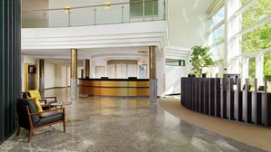A spacious lobby with a reception desk, seating area, and a glass railing overlooking the interior. - Sheraton Offenbach Hotel (Offenbach am Main)