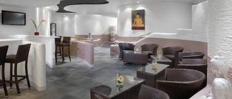 A modern interior with a central seating area, a bar, and a Buddha statue.