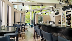 A modern bar area with a long counter, bar stools, and a well-stocked liquor shelf. - Sheraton Offenbach Hotel (Offenbach am Main)