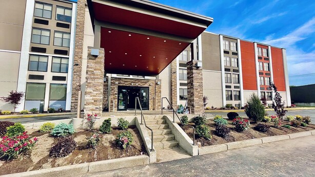 A modern building with a stone facade, large windows, and a covered entrance. - Holiday Inn Express Fall River North by IHG (Fall River)