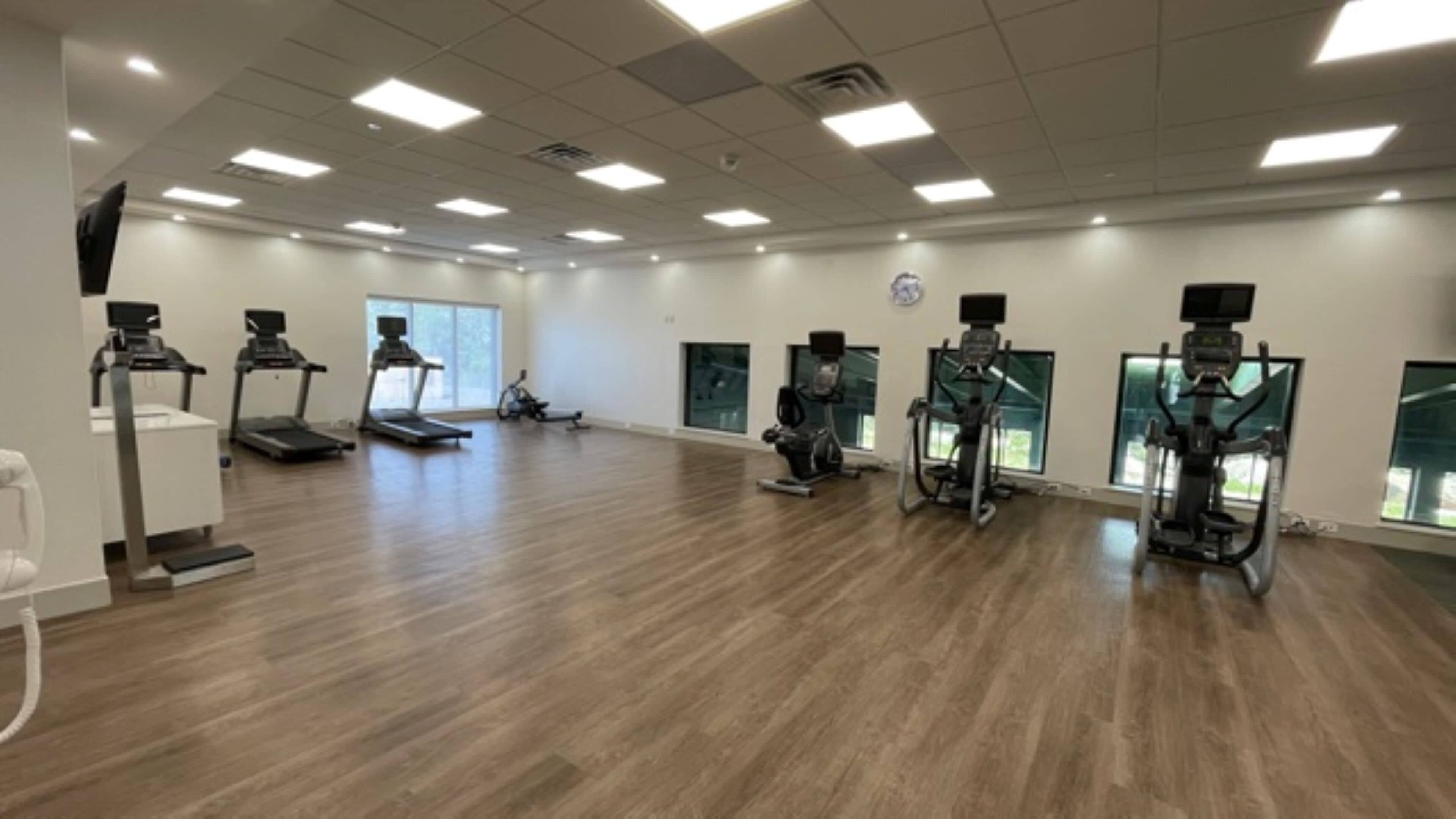 Un gimnasio amplio con numerosas cintas de correr, bicicletas estáticas y elípticas.