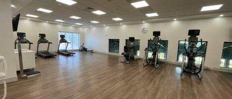 A spacious gym with multiple treadmills, stationary bikes, and elliptical machines.