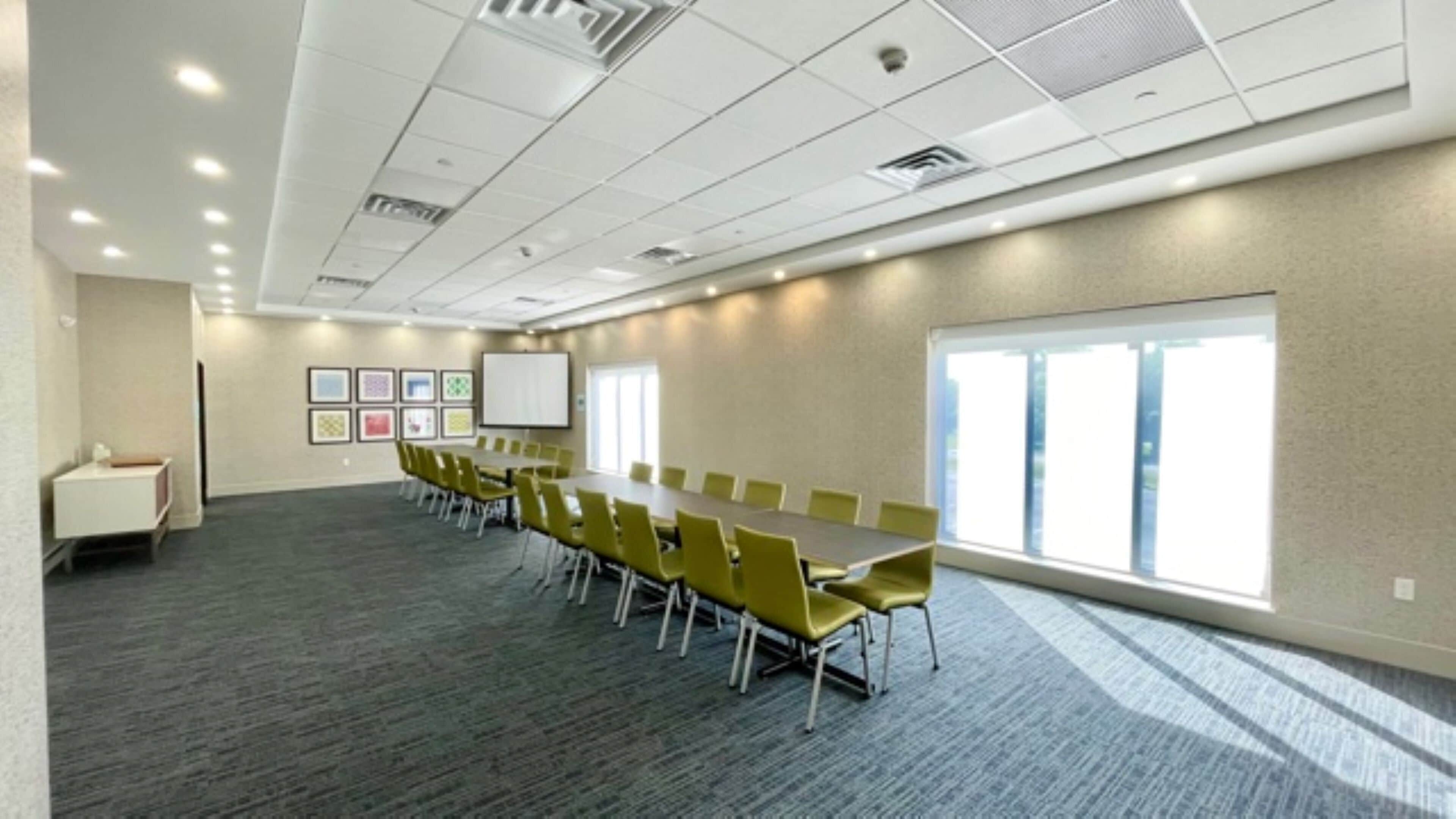 A conference room with a long table, yellow chairs, a whiteboard, and framed pictures on the wall.