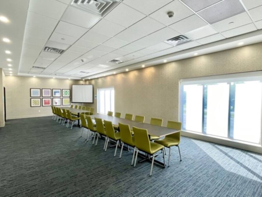 A conference room with a long table, yellow chairs, a whiteboard, and framed pictures on the wall.