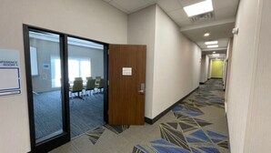A hotel corridor with a conference room, carpeted floors, and a door leading to the room. - Holiday Inn Express Fall River North by IHG (Fall River)