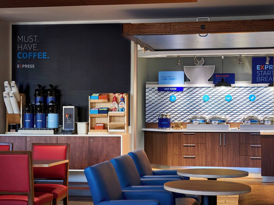 A modern cafe with seating, coffee machines, and a menu board.
