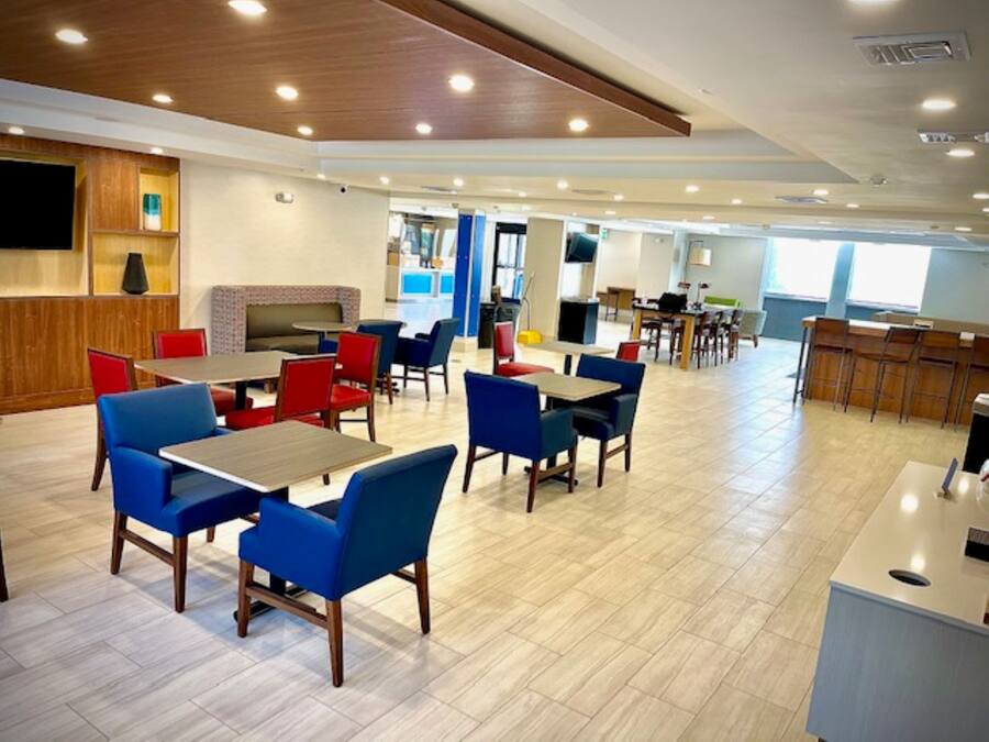 Un espace de restauration moderne avec plusieurs tables et chaises, une cuisine en arrière-plan et un plafond en bois.