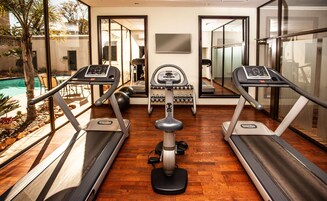 Un gimnasio en casa con cintas de correr, una bicicleta estática y mancuernas.