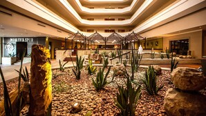 Un vestíbulo de hotel con una zona de estar central, una gran escultura de roca y un diseño de techo moderno.