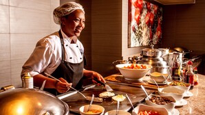 Un chef préparant des plats dans une cuisine équipée de divers ustensiles de cuisine, de bols et d’ingrédients.