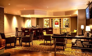 A hotel bar/lounge area with a bar, multiple seating options, and a television screen. - Garden Court Kimberley (Kimberley)