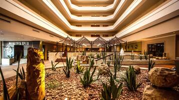 A hotel lobby with a central seating area, a large rock sculpture, and a modern ceiling design.