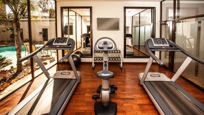 Un gimnasio en casa con cintas de correr, una bicicleta estática y mancuernas.