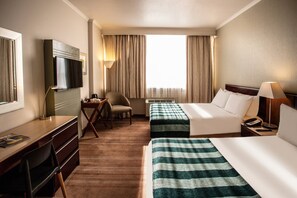 A hotel room with a desk, two beds, a TV, a chair, and a window with curtains. - Garden Court Kimberley (Kimberley)